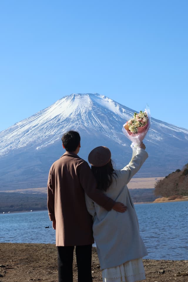 背對鏡頭望向富士山，手舉花束