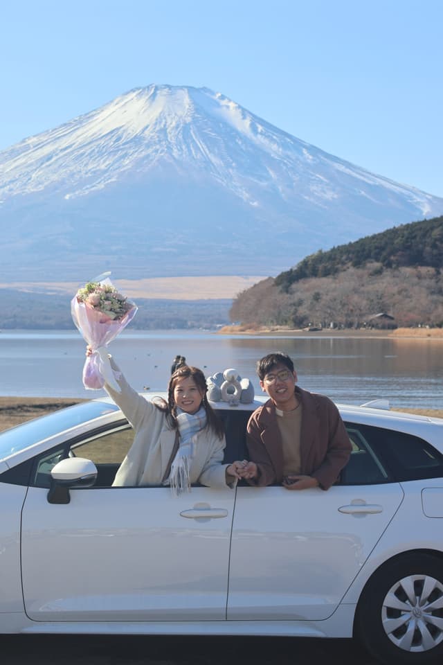 兩人自車窗探出，高舉花束微笑
